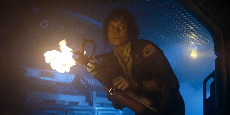 Ripley holding a flame-thrower as she faces the camera