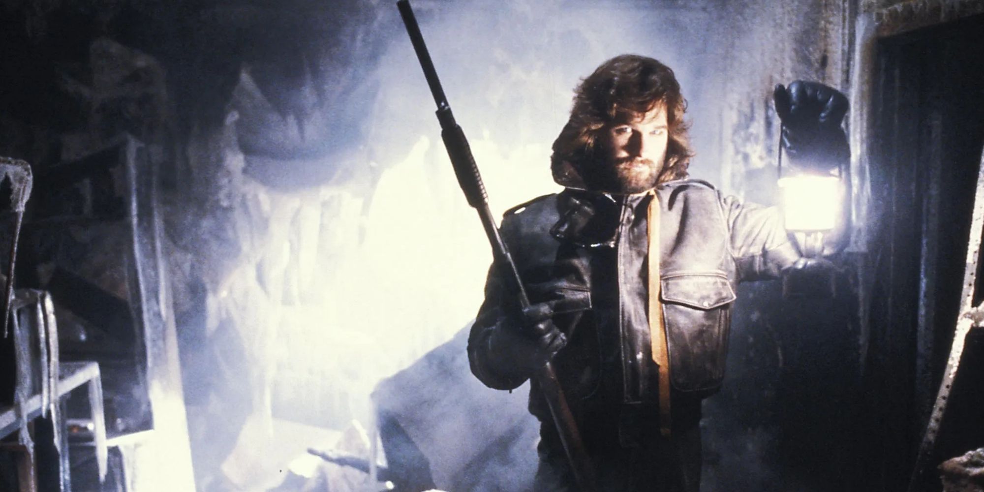 Macready (Kurt Russell) holding a lantern and a gun in 'The Thing' (1982)