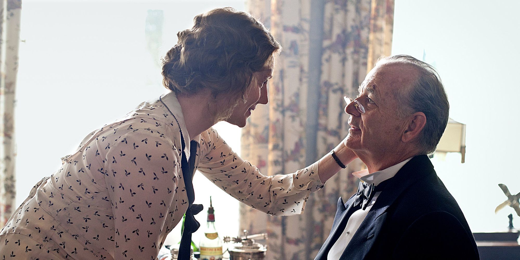 A woman gently touches a man&rsquo;s face