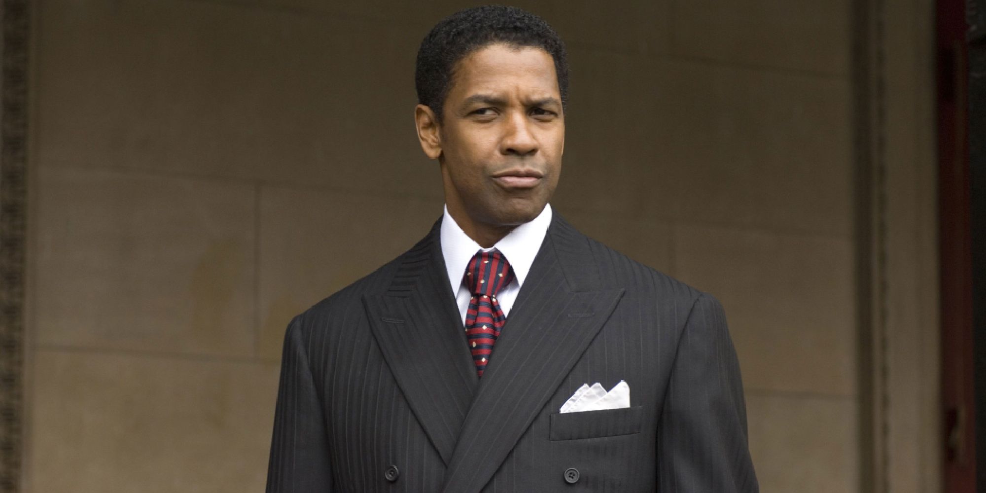 Denzel Washington as Frank Lucas smirking while looking intently in American Gangster