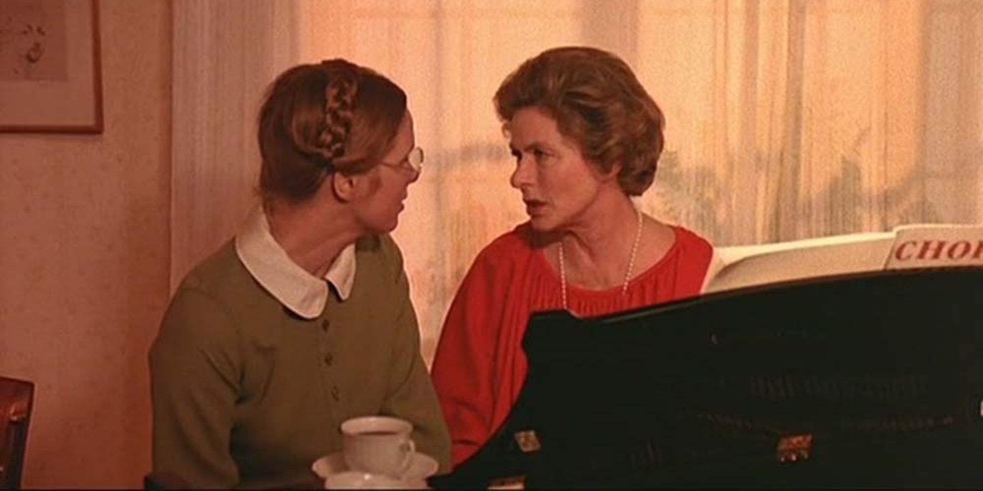Liv Ullman and Ingrid Bergman as Eva and Charlotte facing each other and talking while sitting behind a piano in the film Autumn Sonata (1978)