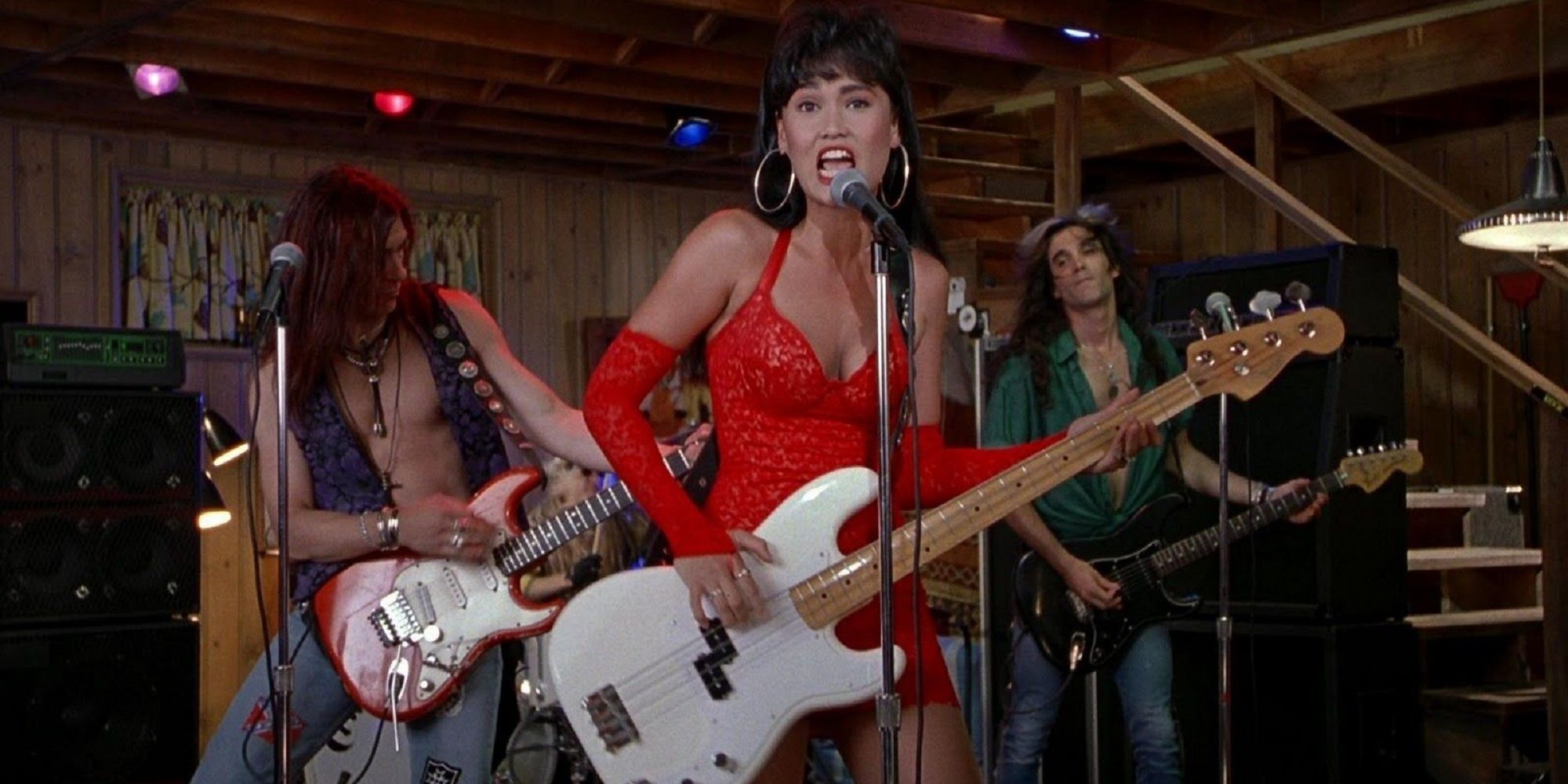 Cassandra Wong in a red dress performing with her band and playing bass guitar in Wayne's World.