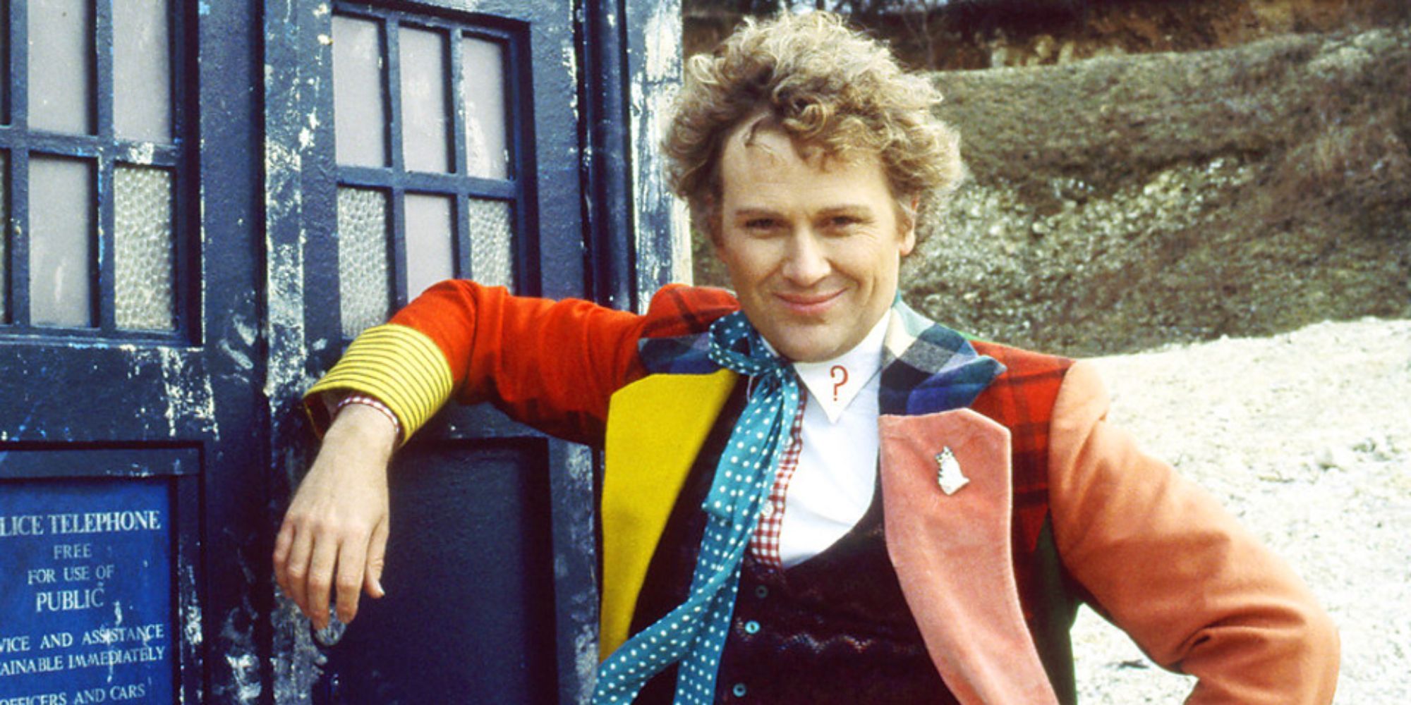 O Sexto Doctor encostou-se na TARDIS, rindo