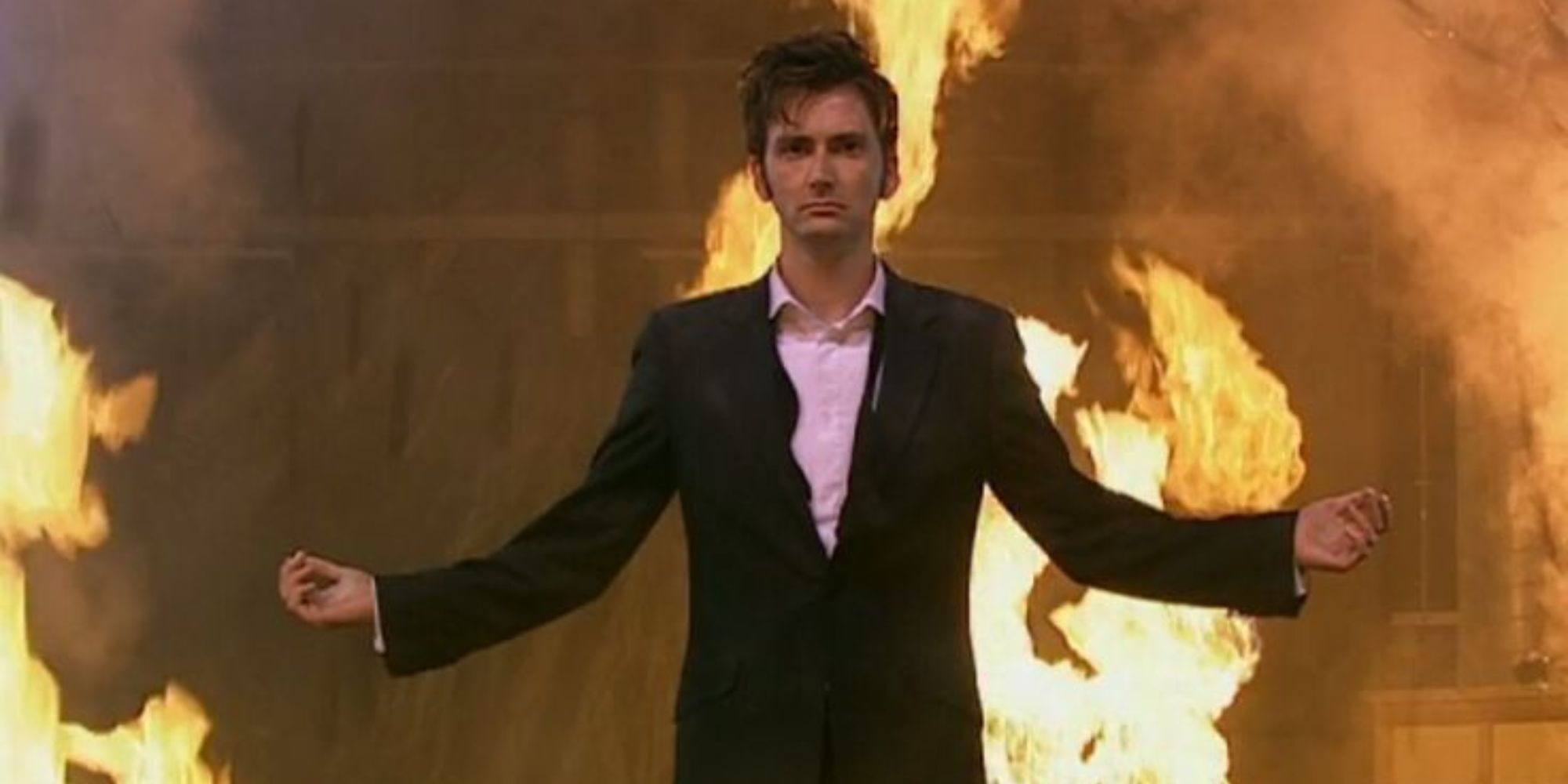 10th Doctor in a tuxedo with his arms outstretched surrounded by fire