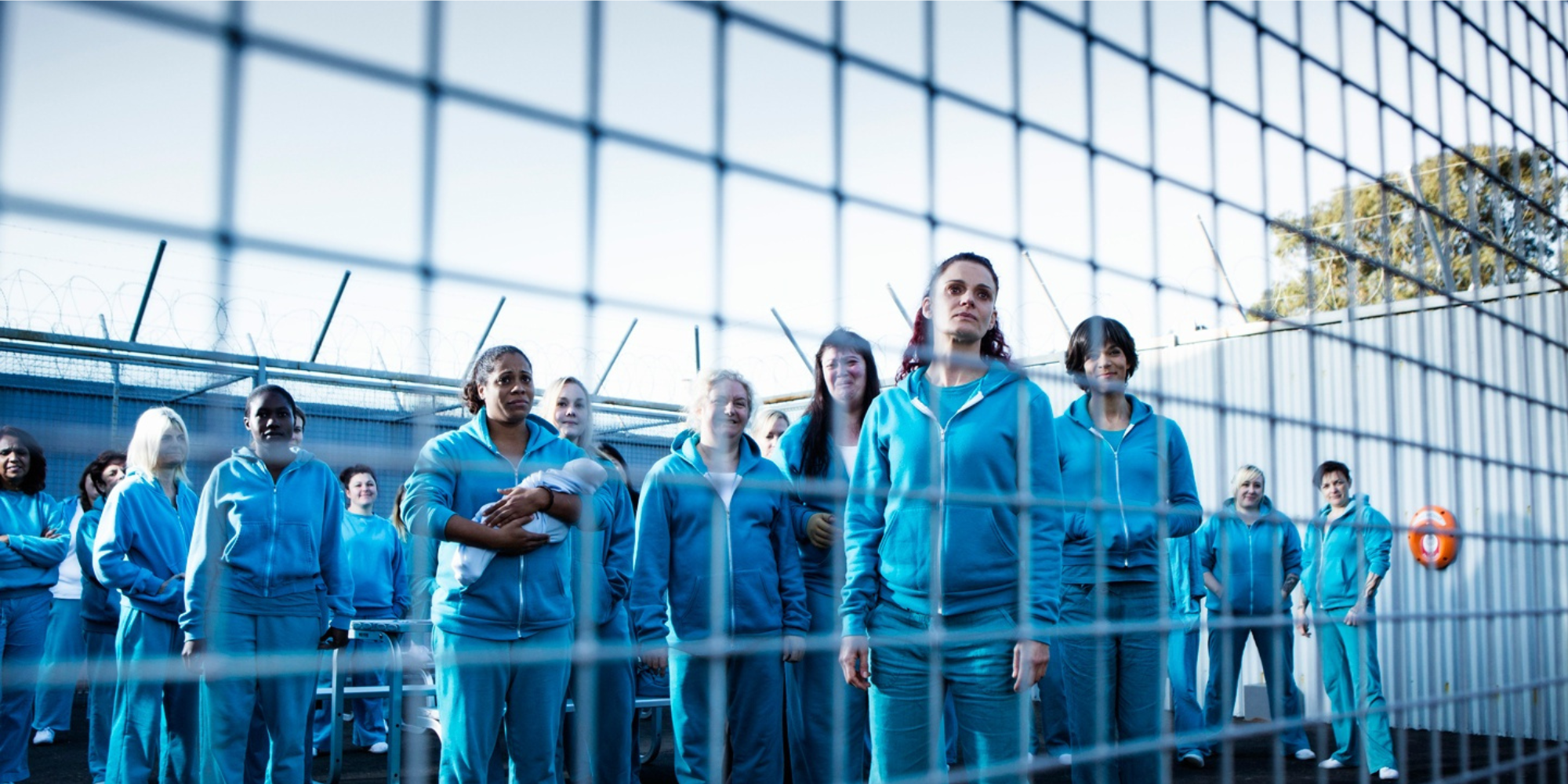 Inmates of 'Wentworth' standing behind a gate