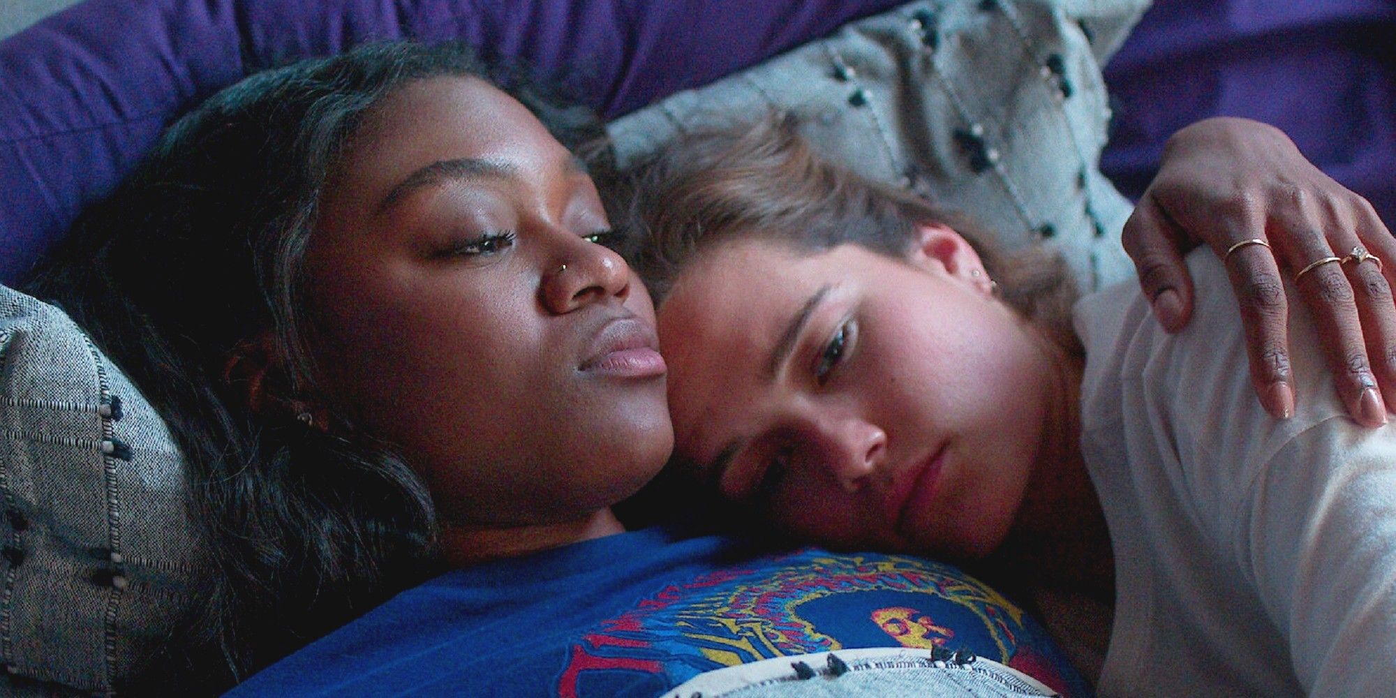 Two teen girls lying in bed holding each other