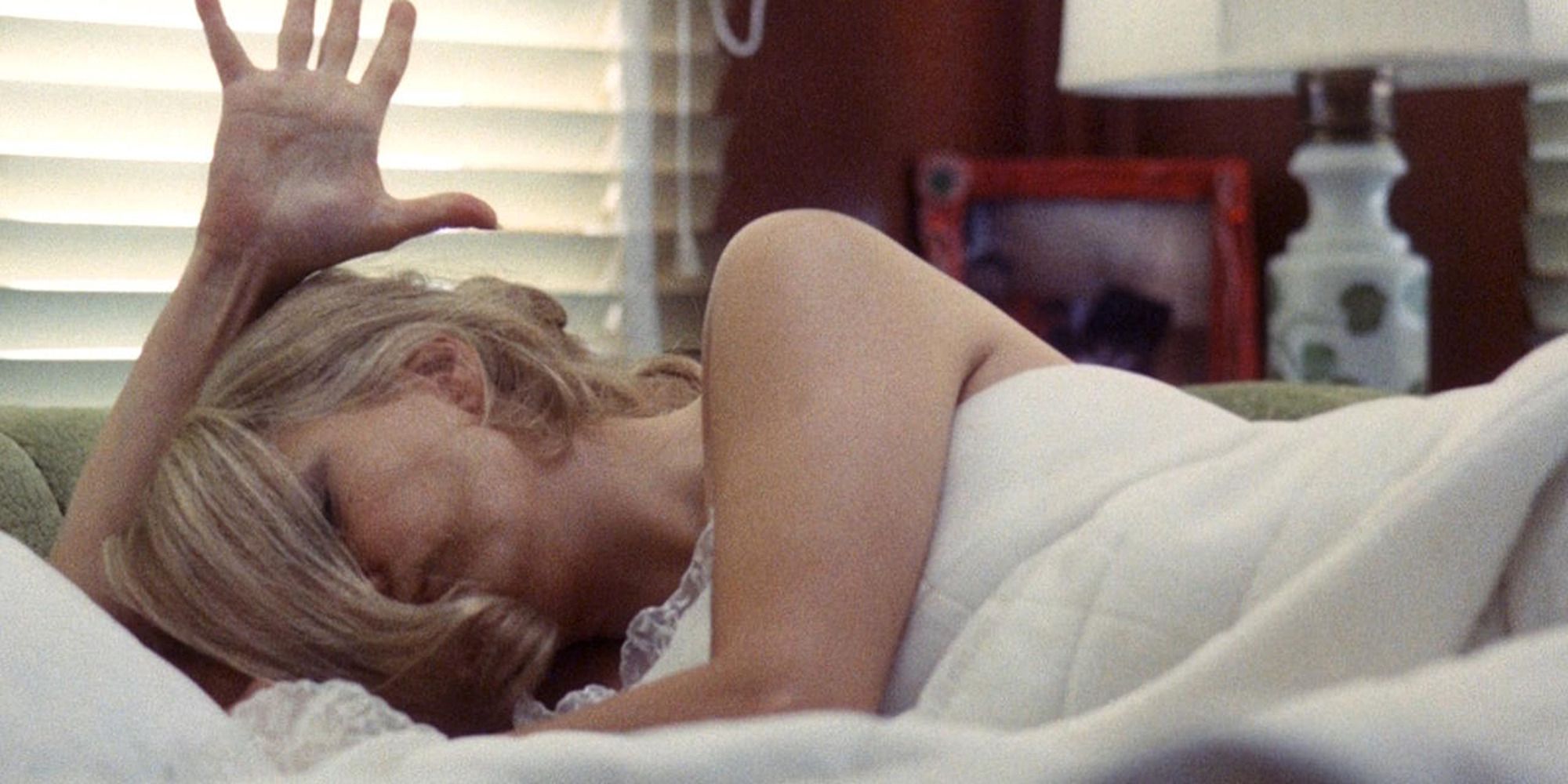 Gena Rowlands lying topless in bed, covered by bedsheets