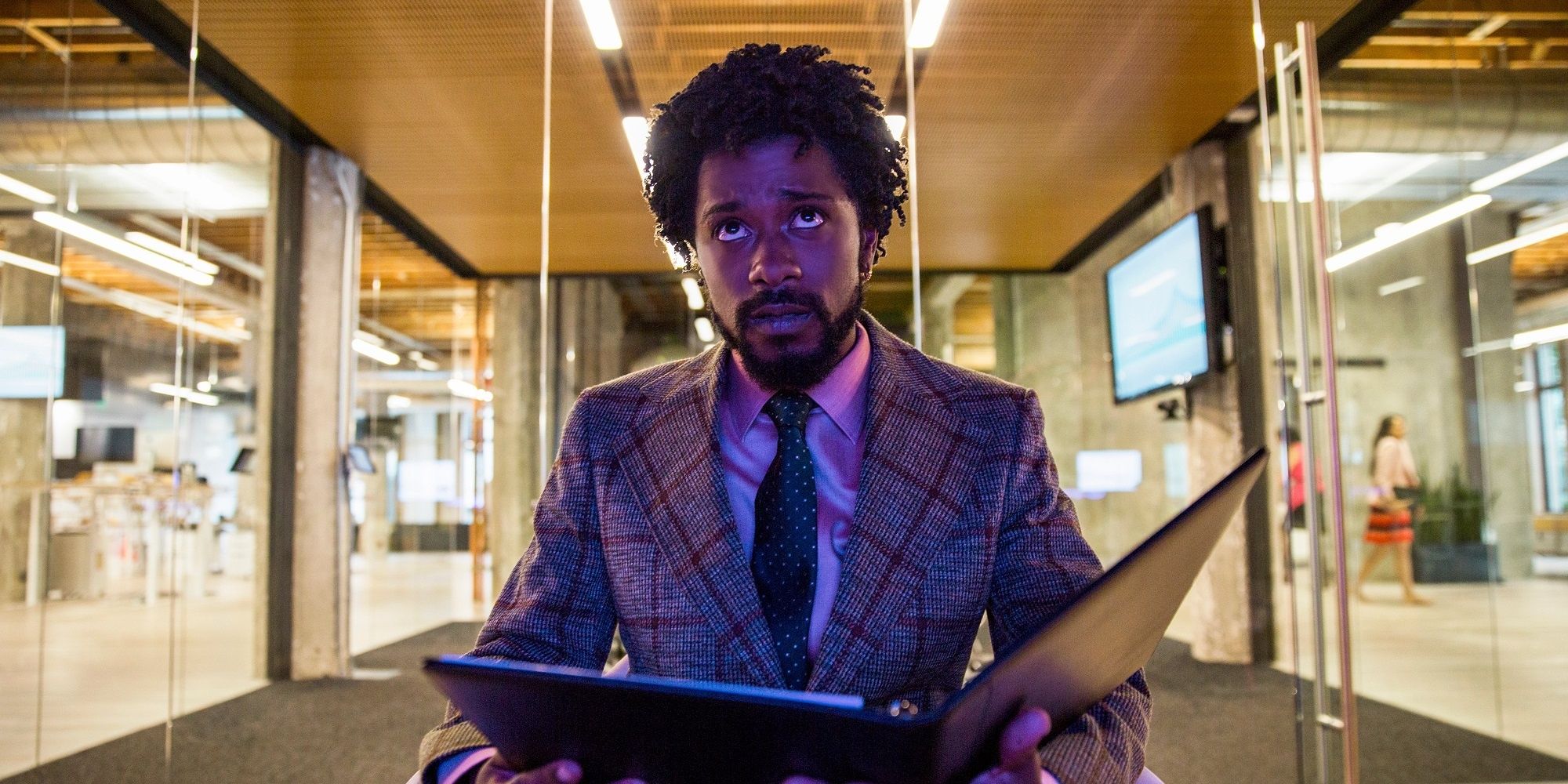 Cash assis par terre avec un classeur dans Sorry To Bother You.