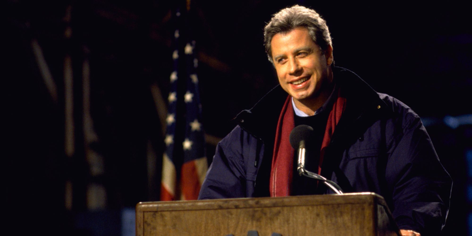 John Travolta is taking the podium in Primary Colors.