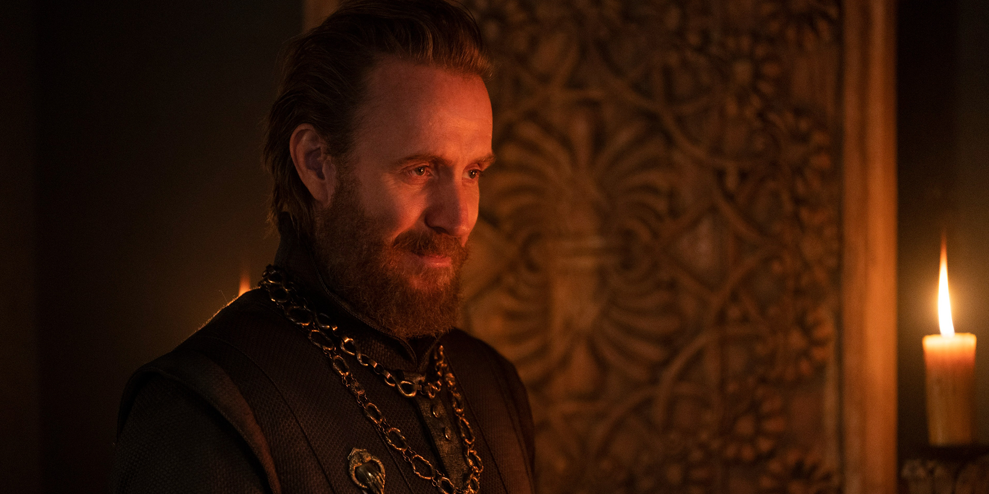 Otto Hightower stands in a dark room with a lit candle in House of the Dragon
