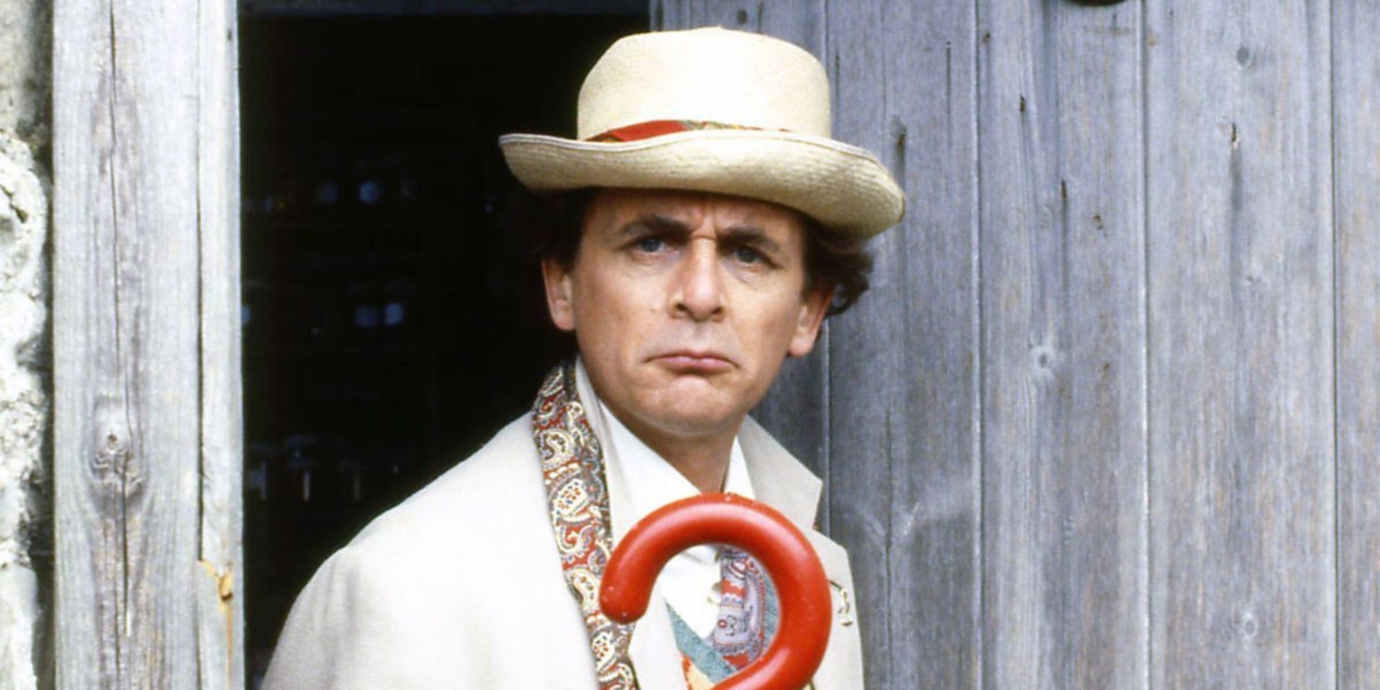 7th Doctor frowning at the camera while holding his question mark umbrella