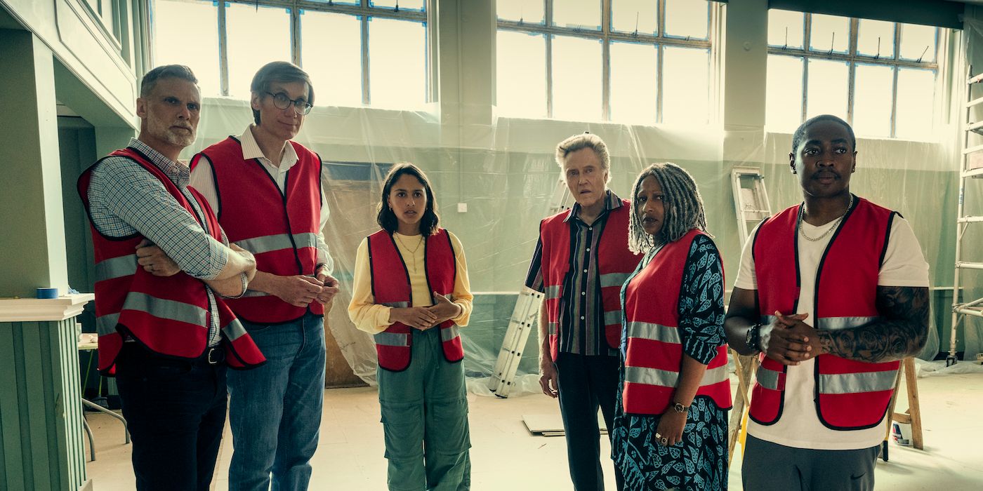 The cast of The Outlaws standing in red vests all looking at something.