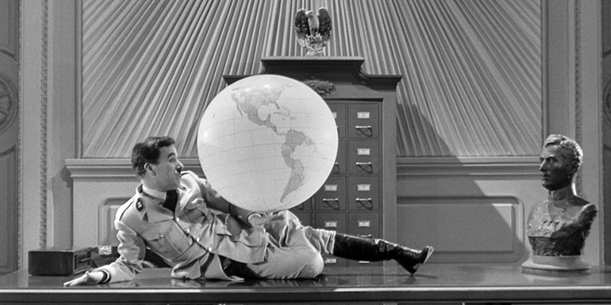 Charles Chaplin as The Great Dictator plays with an inflated globe on his desk