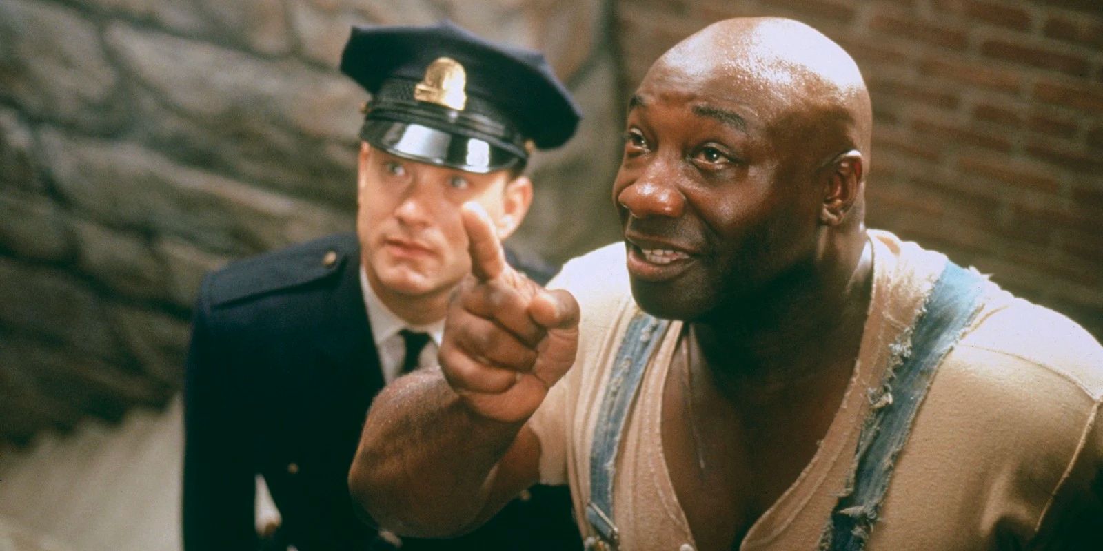 John Coffey (Michael Clarke Duncan) smiling and point upward while Paul Edgecomb (Tom Hanks) watches in The Green Mile
