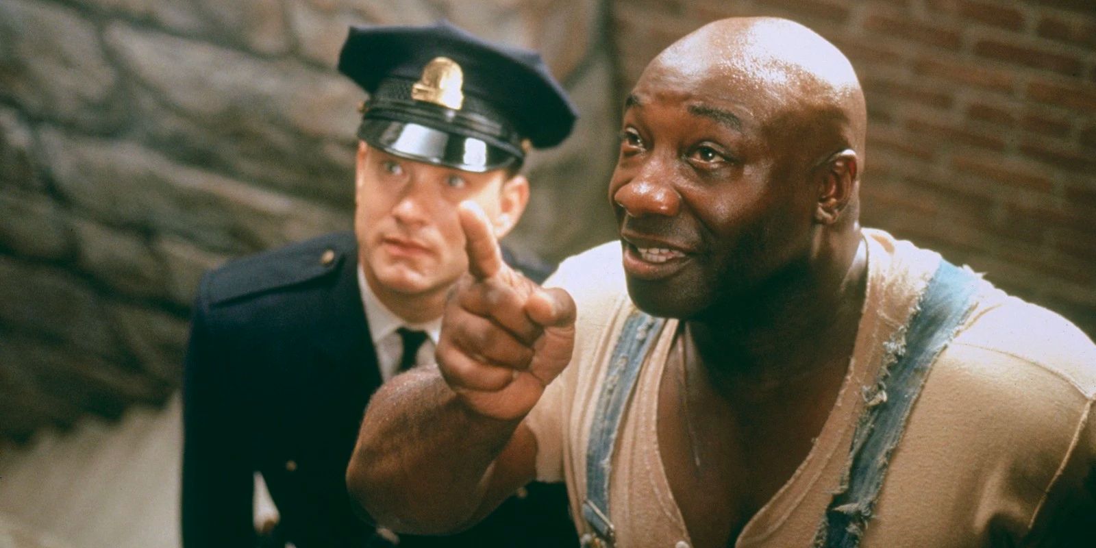 John Coffey (Michael Clarke Duncan) mira hacia arriba con una sonrisa mientras Paul Edgecombe (Tom Hanks) mira en La Milla Verde.