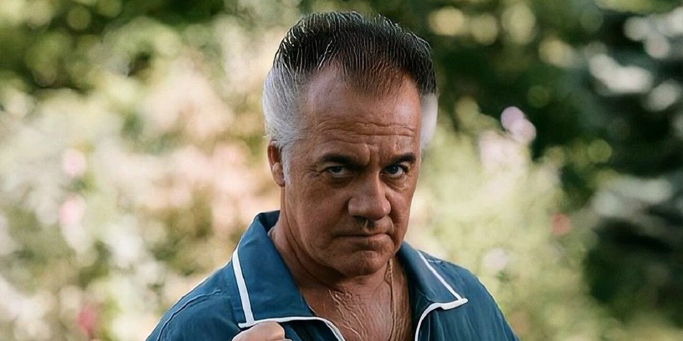 Tony Sirico as Paulie Walnuts, standing outside, wearing a blue collared shirt, and looking serious in The Sopranos