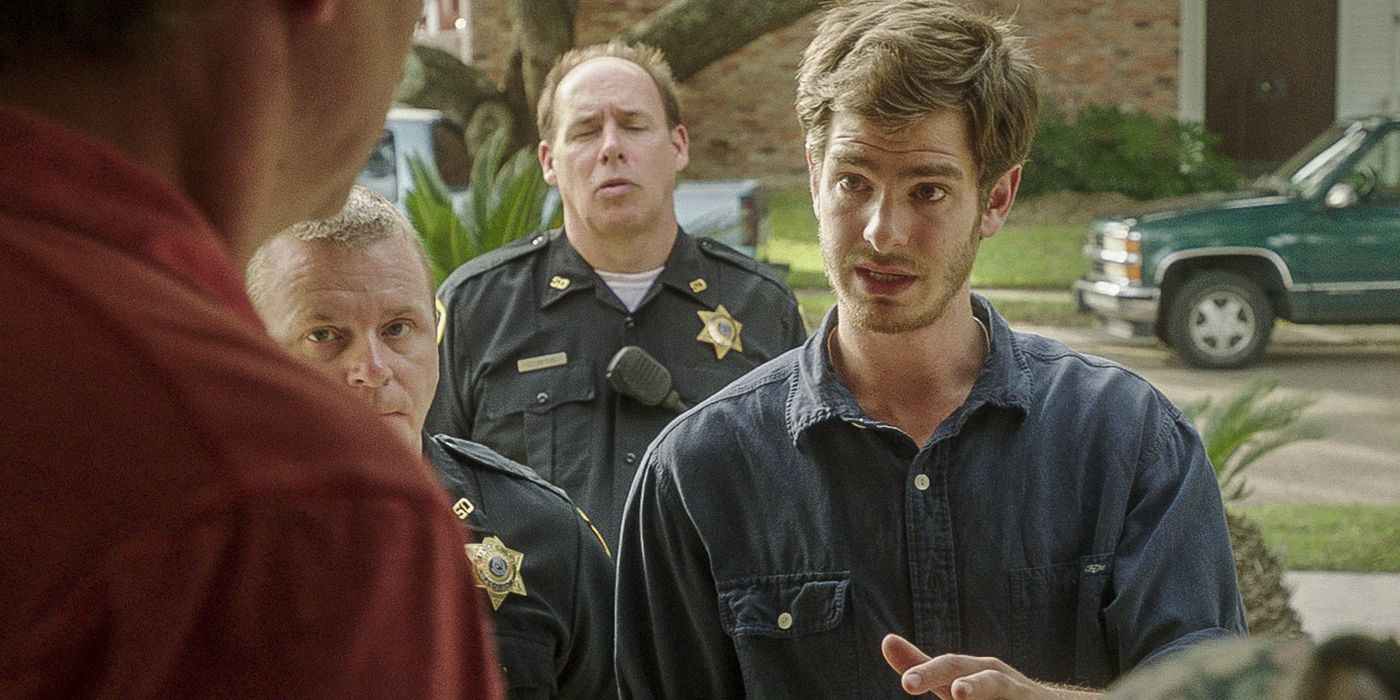 Andrew Garfield as Dennis Nash talking to people inside a house in the film 99 Homes.