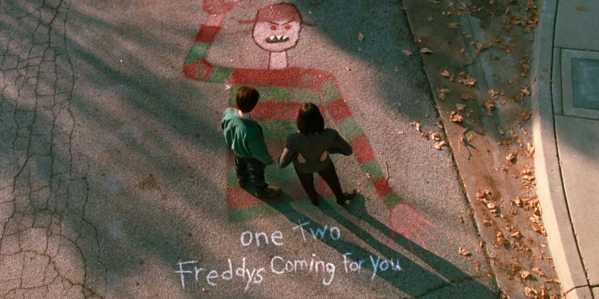 Two people standing on a chalk drawing of Freddy Krueger