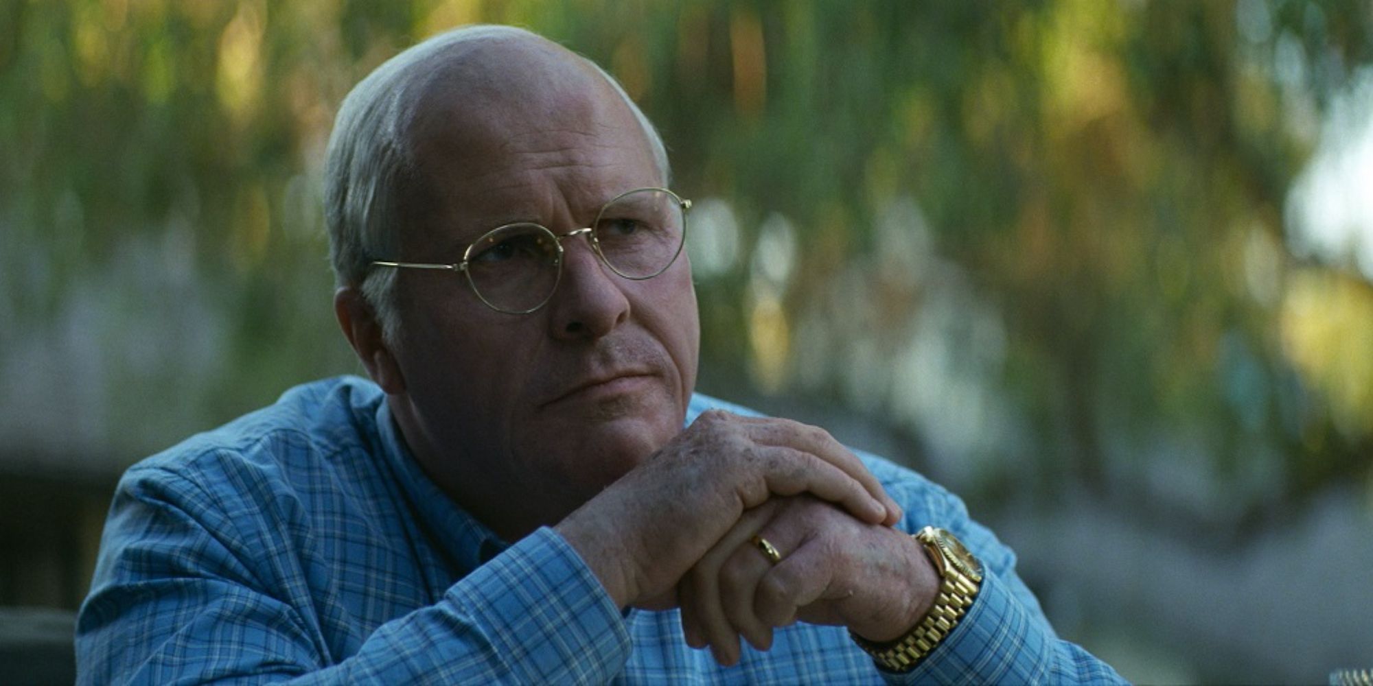 Dick Cheney (Christian Bale) contemplates an offer while sitting outside in the shade. 