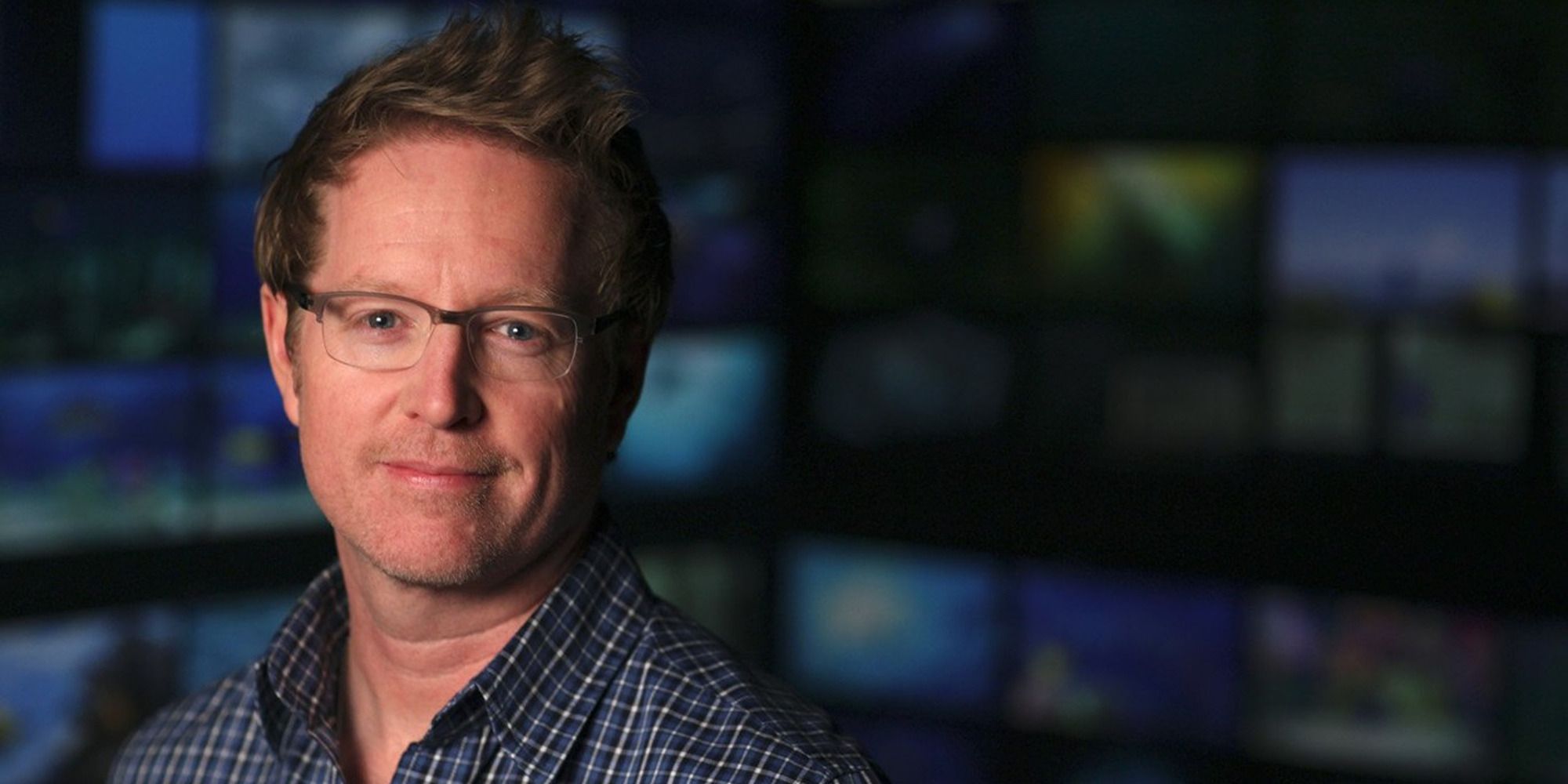 Andrew Stanton wearing glasses and a blue shirt, smiling at the camera