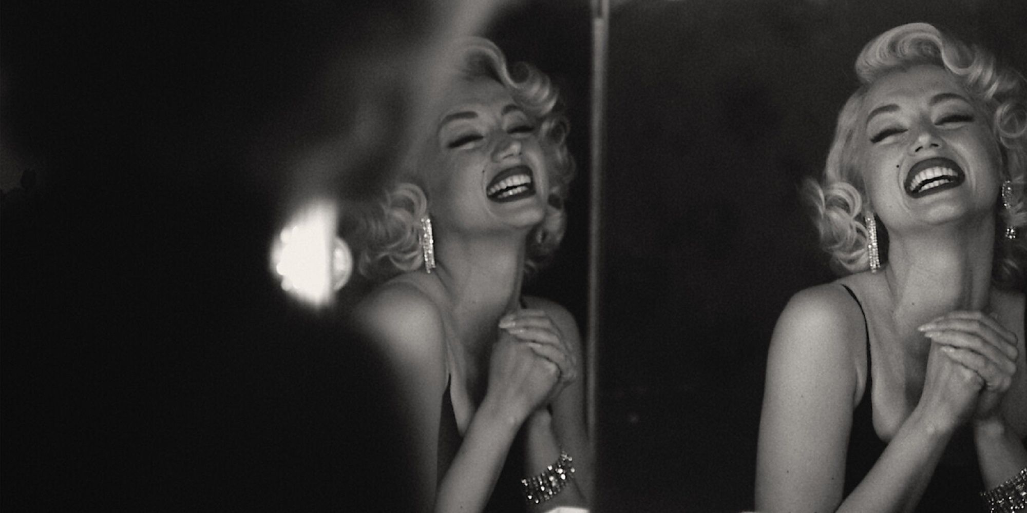 Ana de Armas as Marilyn Monroe smiling in front of a mirror in 'Blonde.'