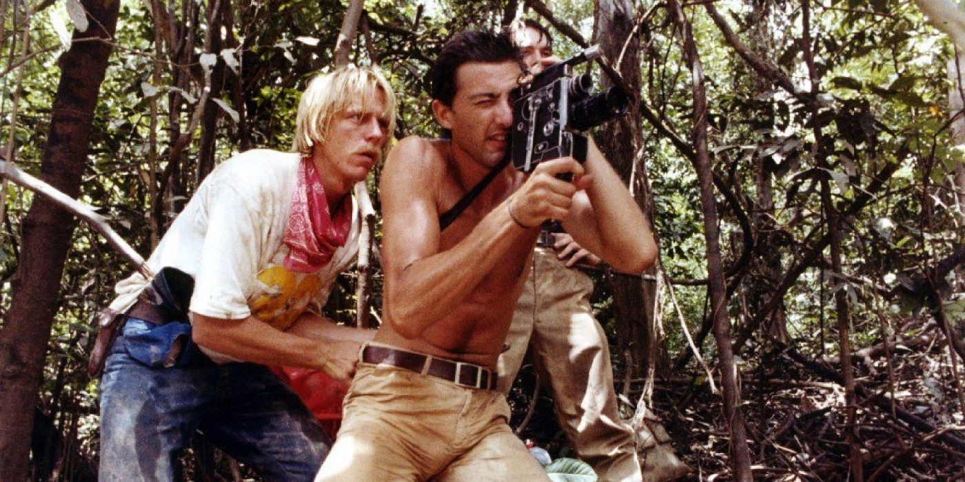 Luca Barbareschi and Perry Pirkanen as Mark Tomaso and Jack Anders, standing in the woods and recording on a video camera in Cannibal Holocaust