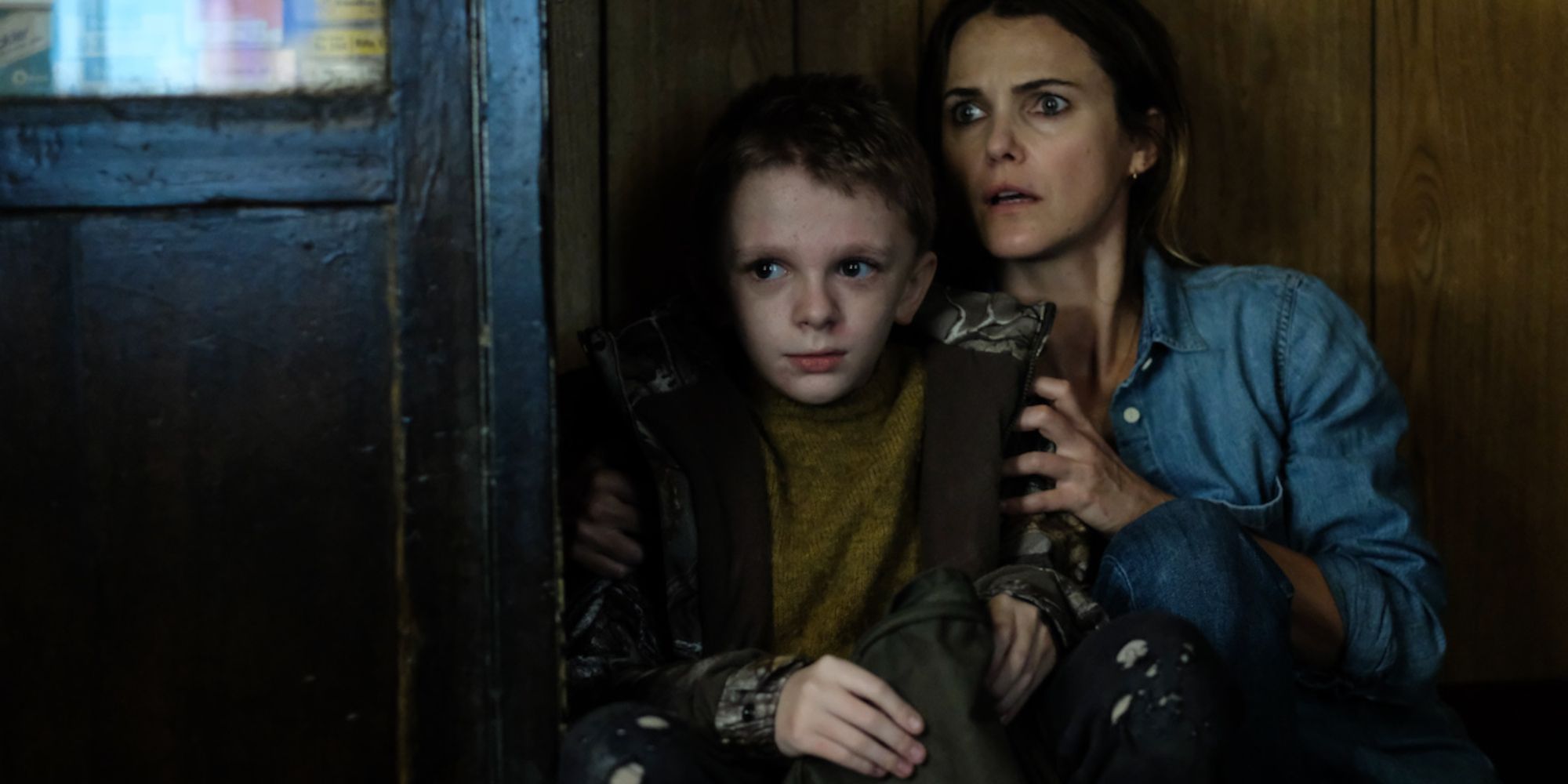 Keri Russell and Jeremy T. Thomas hiding in the corner of the house 