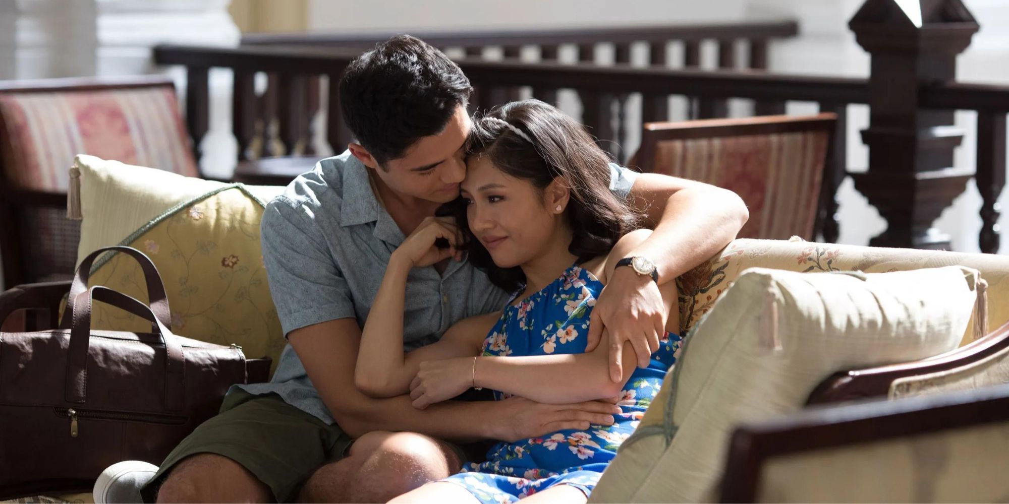 Nick and Rachel from Crazy Rich Asians cuddling on a couch