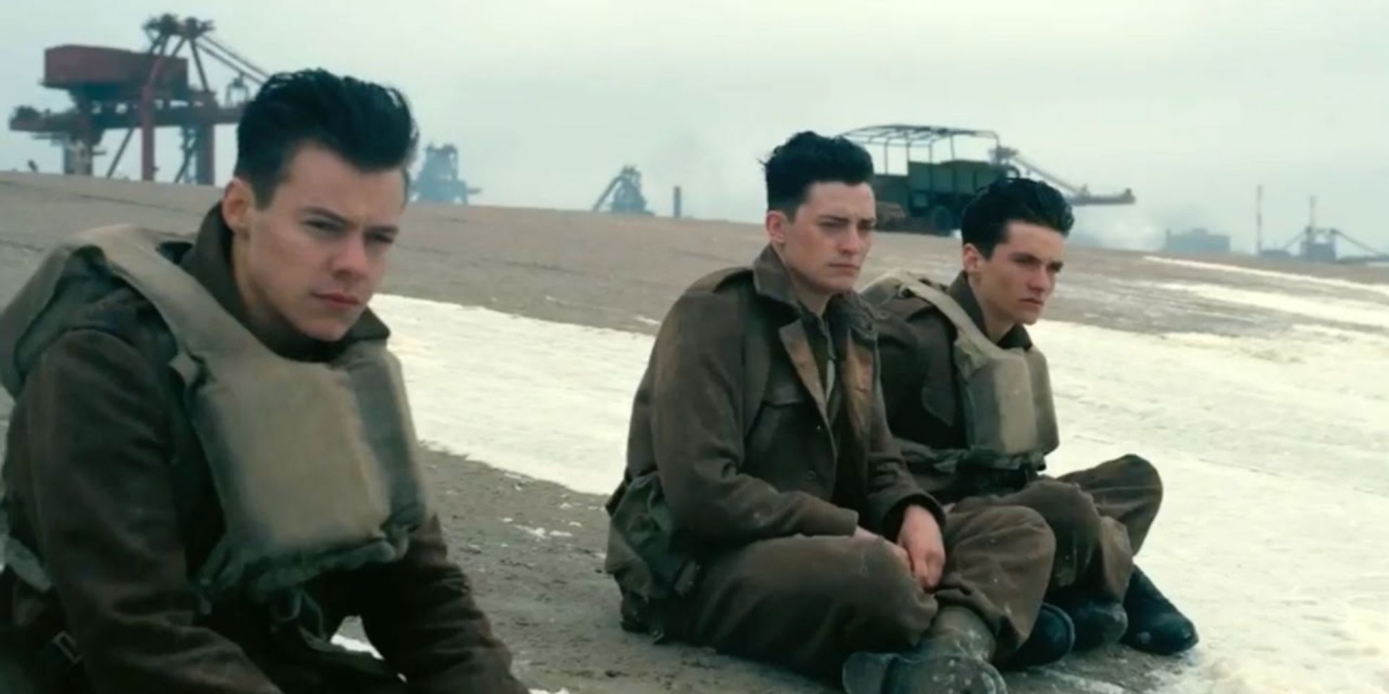 Harry Styles, Aneurin Barnard & Fionn Whitehead sitting on a beach in Dunkirk