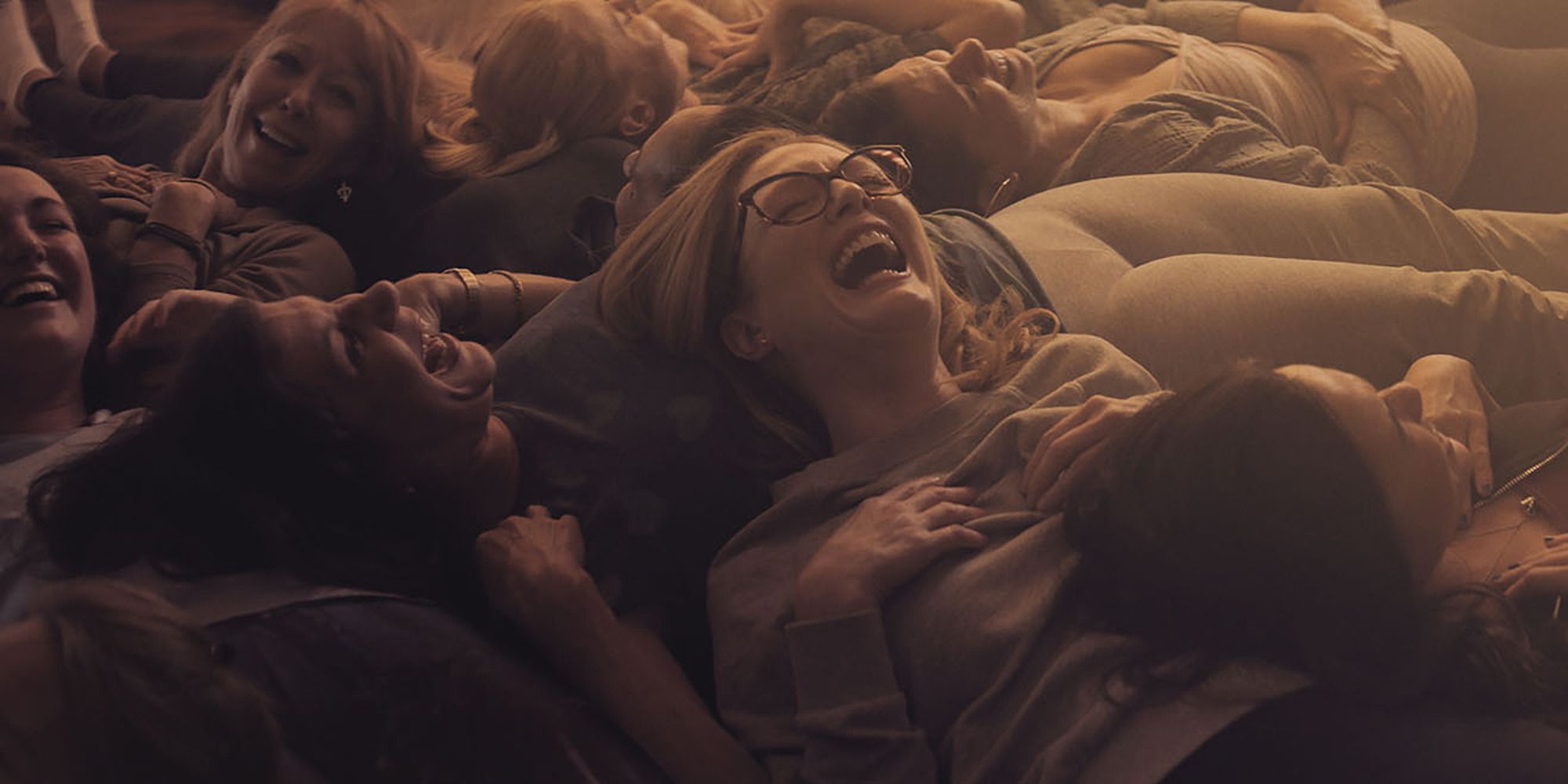 Julianne Moore allongée avec d'autres femmes, riant dans Gloria Bell.