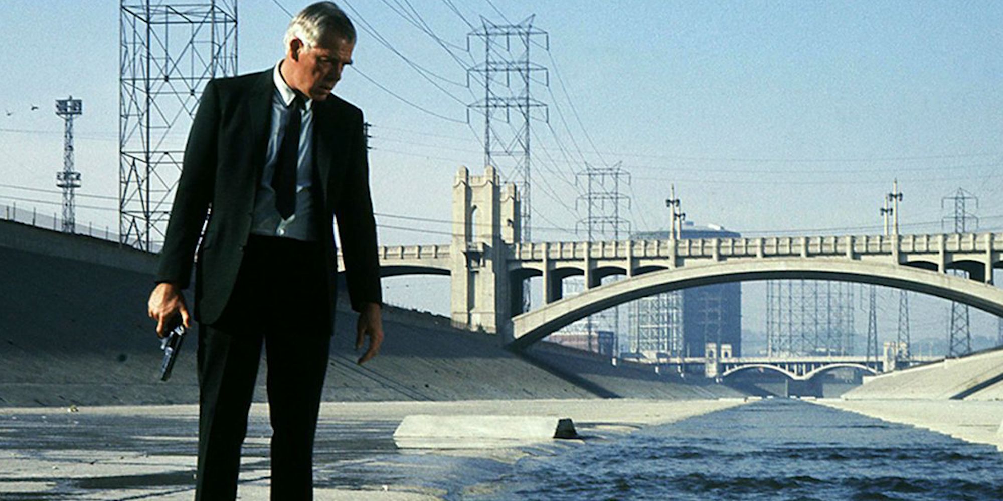 Lee Marvin as Walker holding a gun and looking down at something in the film Point Blank