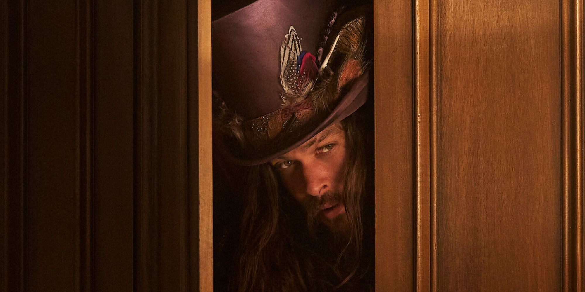 Jason Momoa as Flip, wearing a fancy top hat and looking out from behind a door in 'Slumberland.'