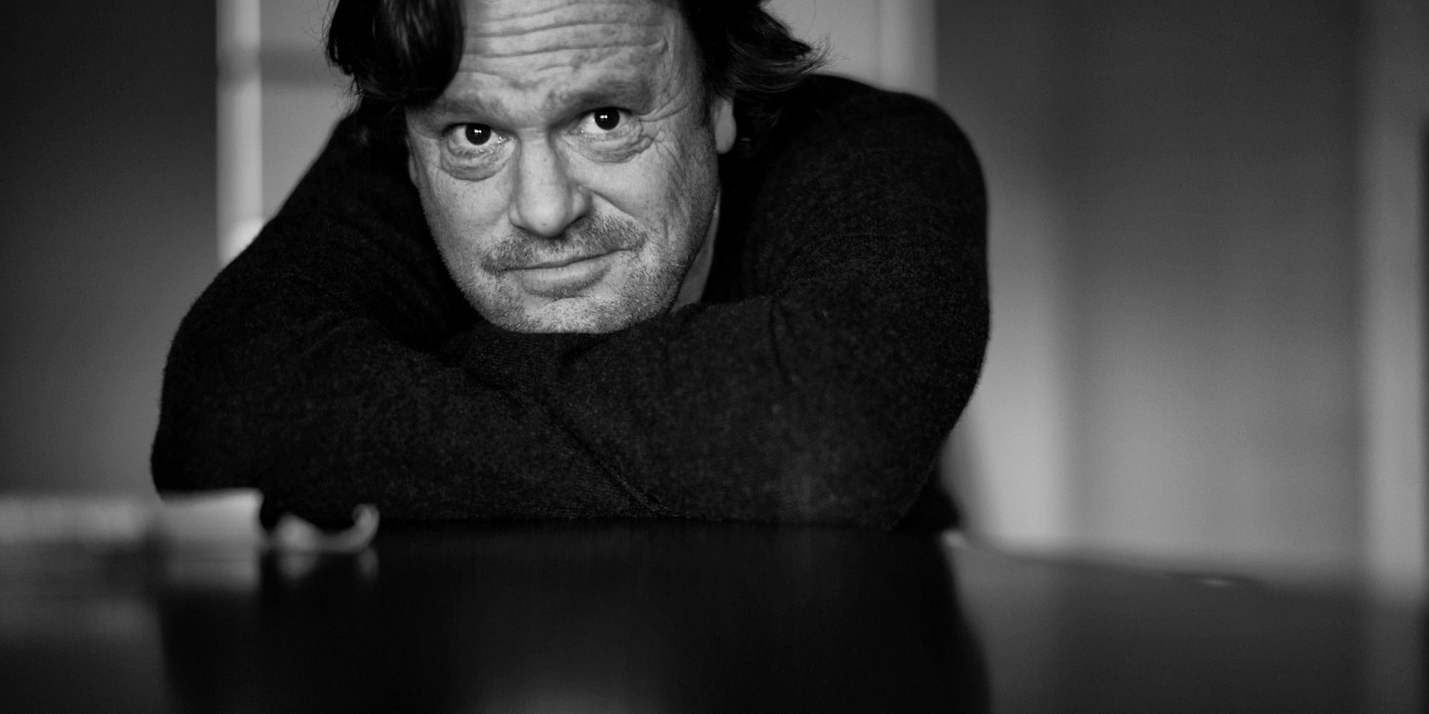 Steve Kloves leaning on a table, photograph in black and white