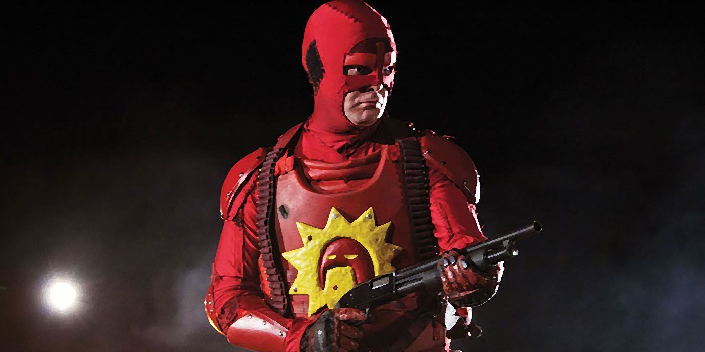 Vigilante the Crimson Bolt wields a shotgun while dressed in a red superhero costume in the streets at night.