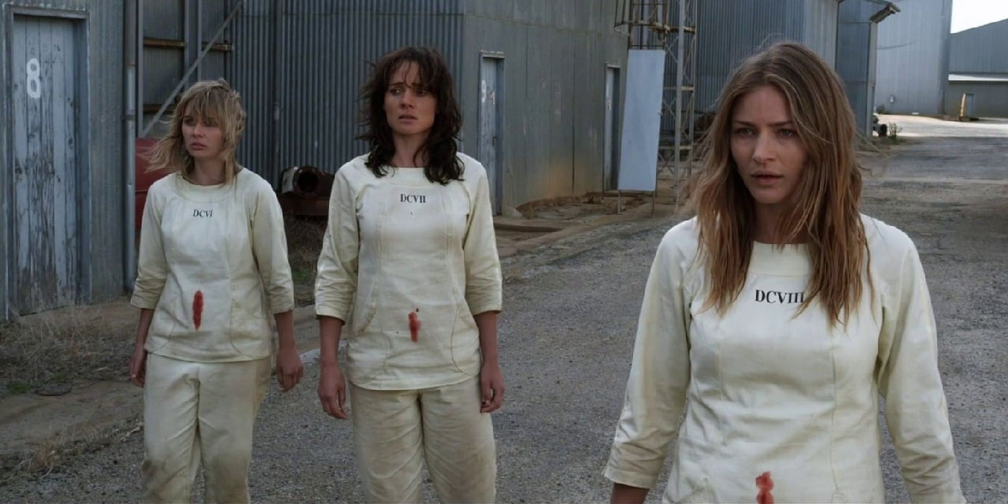 Three women stand with blood-stained shirts