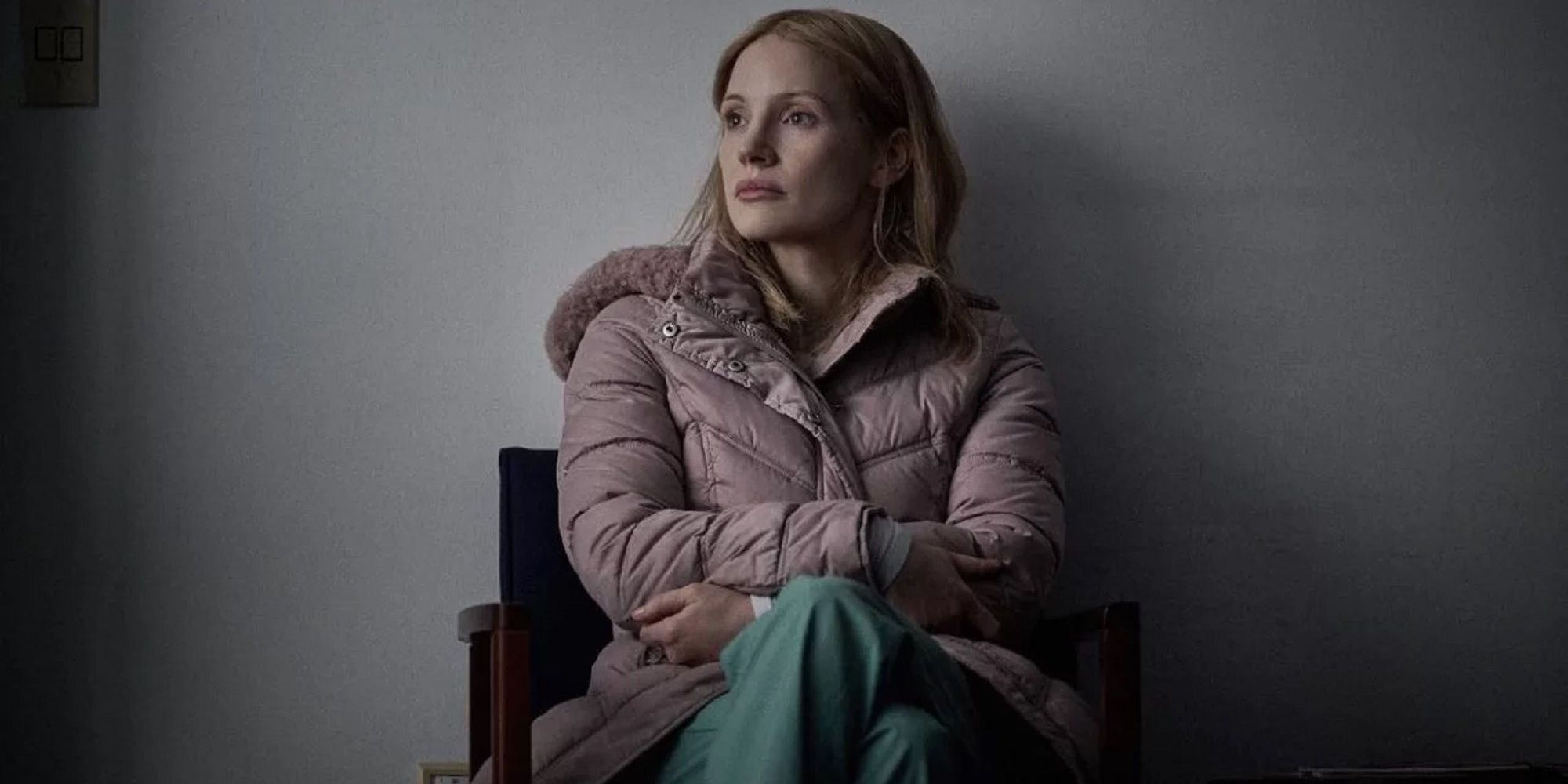 Jessica Chastain as the nurse Amy Loughren in 'The Good Nurse,' sitting in a chair against a blank, white wall.