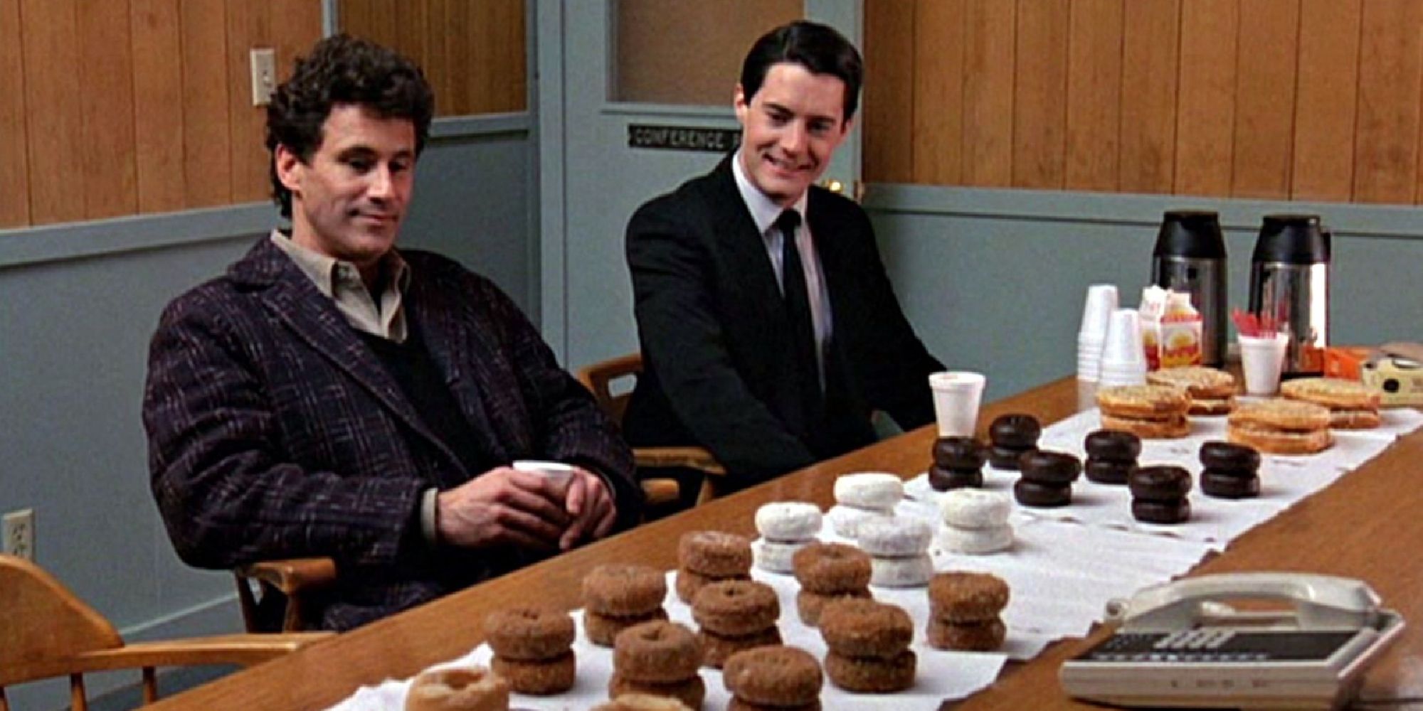 Kyle MacLachlan and Michael Ontkean as Dale Cooper and Sheriff Truman, sitting at a table full of donuts in Twin Peaks