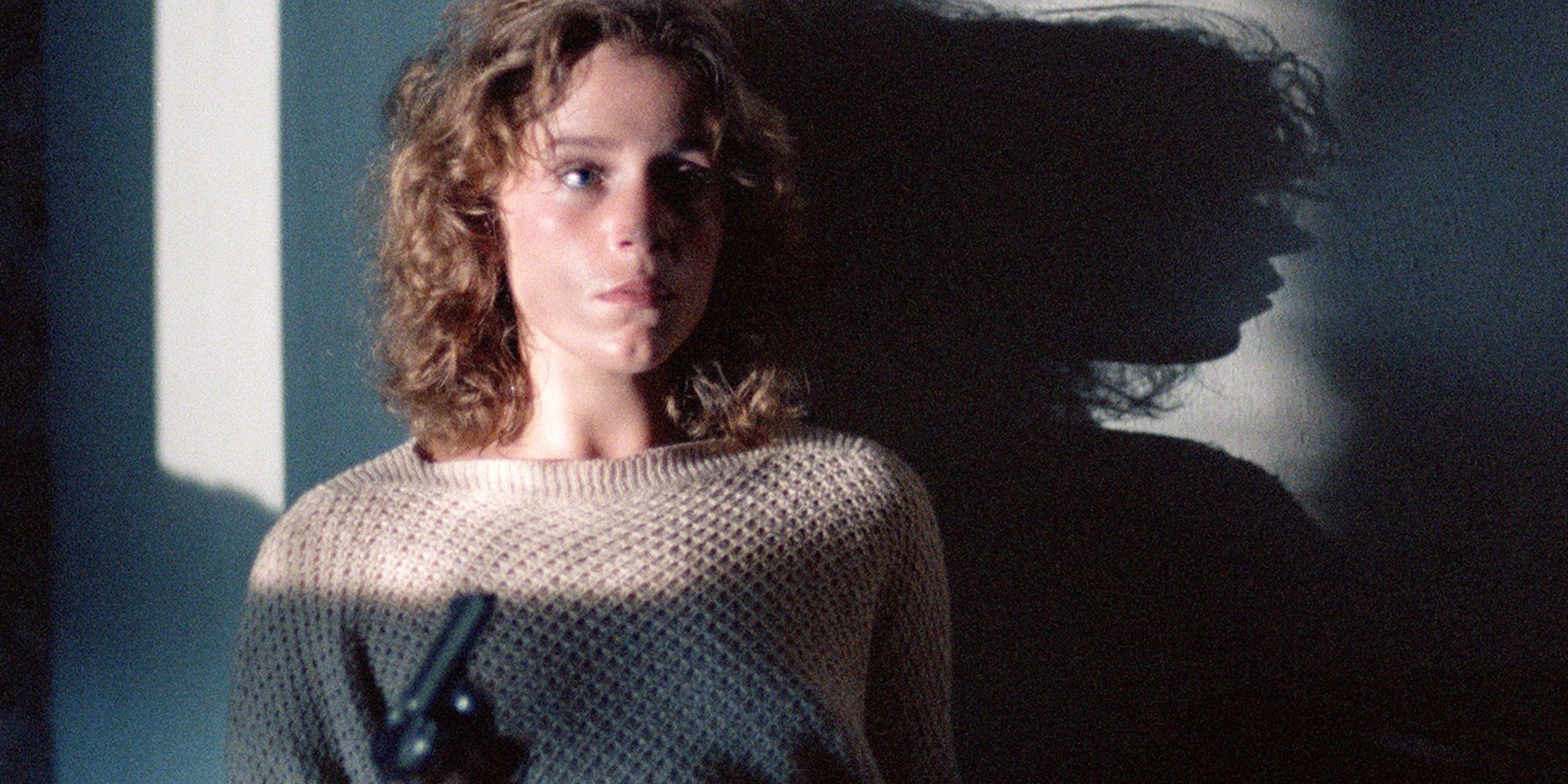 Abby holding a gun and looking scared in Blood Simple