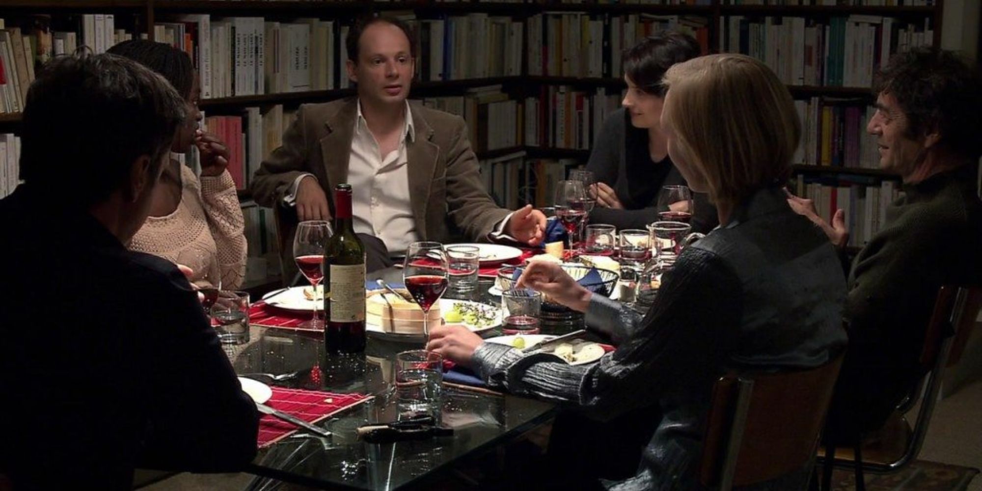 A family sits at a dinner table surrounded by bookshelves