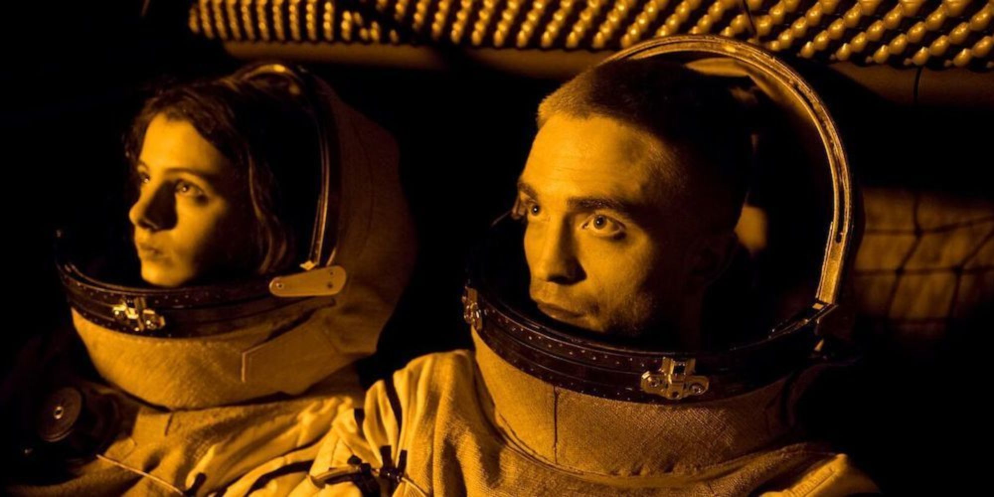 Two astronauts, one man and one woman look through the window towards the sun aboard their spacecraft