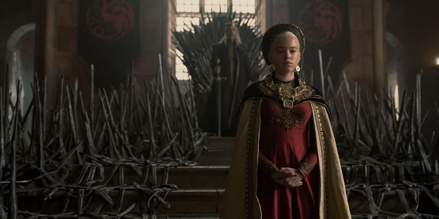 Milly Alcock as Rhaenyra Targaryen standing in the throne room with Paddy Considine as Viserys I behind her in House of the Dragon