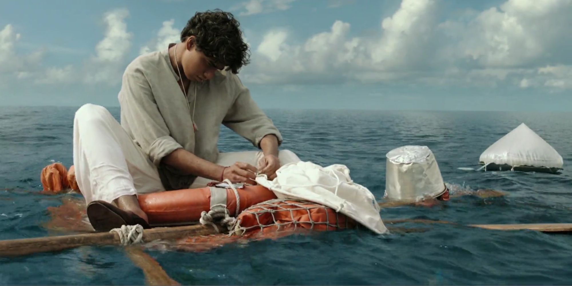 Pi builds a raft out of life preserver rings, tarps, rope, and oars to get away from the tiger on his lifeboat
