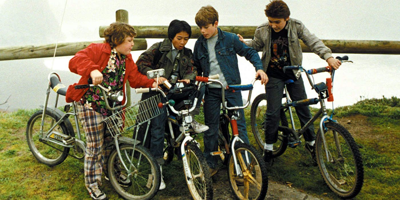 Mouth (Corey Feldman), Mikey (Sean Astin), Data (Ke Huy Quan), and Chunk (Jeff Cohen) on bikes in The Goonies