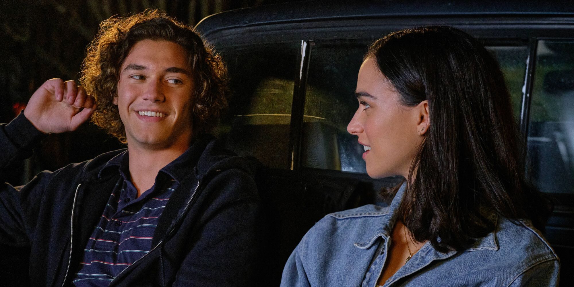 A couple smile at each other at the back of a truck