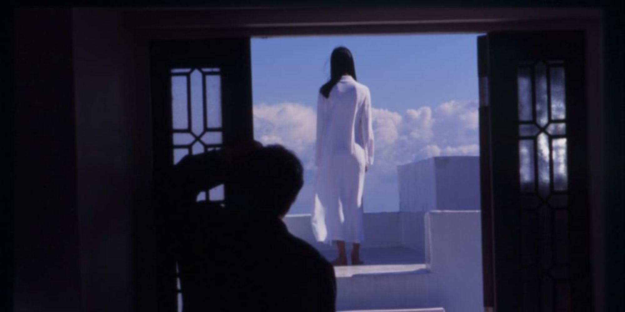 A man staring at a woman dressed in a white dress against a blue sky background in Audition (1999)