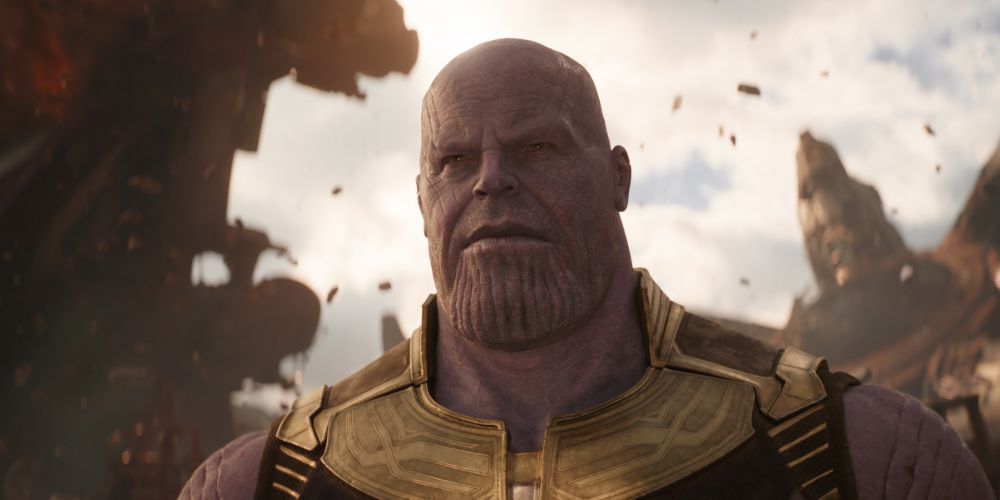 Thanos regardant attentivement avec des montagnes en arrière-plan dans 'Avengers : Infinity War'.