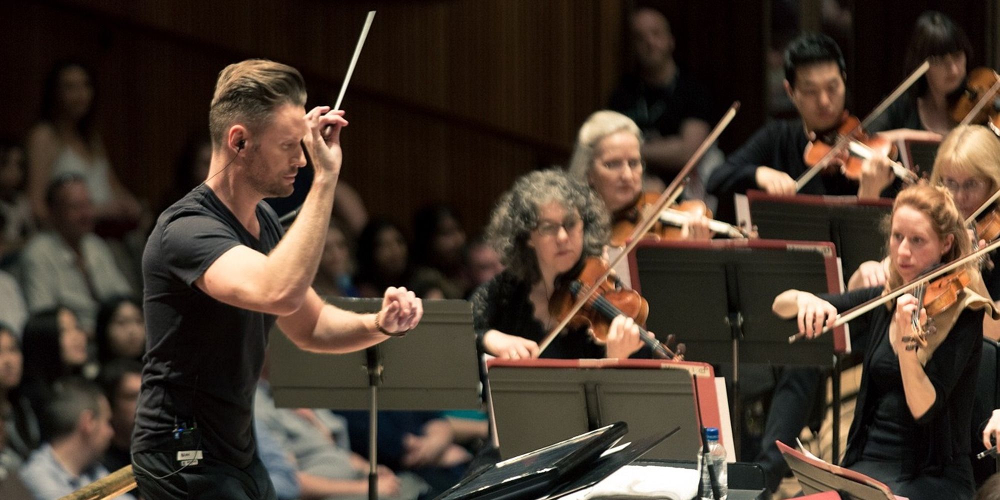 Brian Tyler conducting an orchestra in front of a crowd