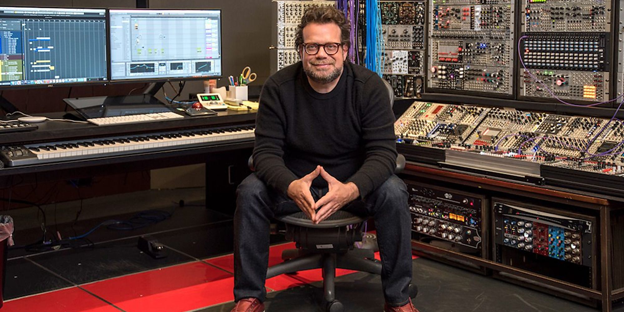 Christophe Beck sitting on a stool in his mixing studio
