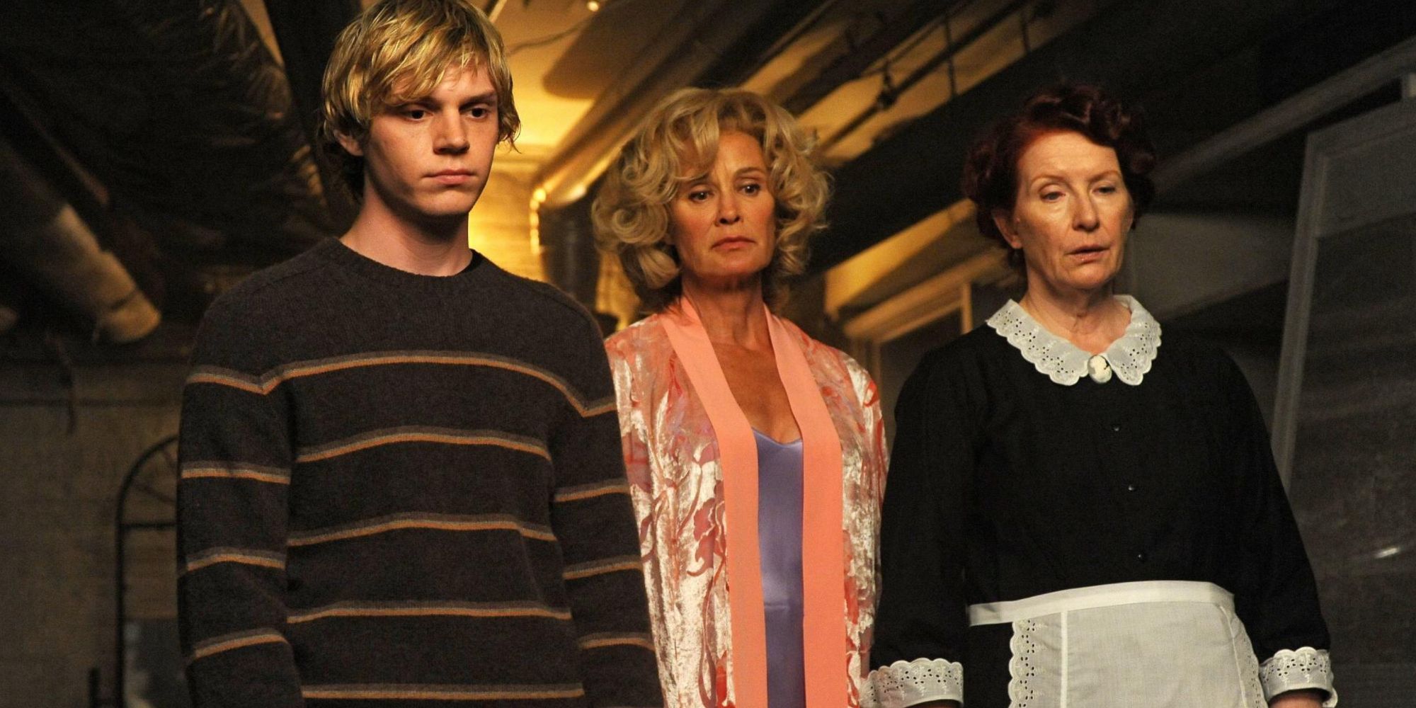 Evan Peters, Jessica Lange and Frances Conroy looking down at something 