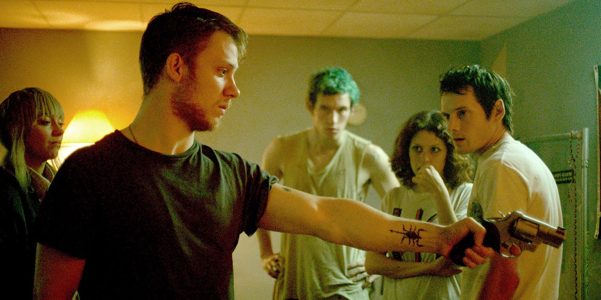 Joe Cole's character, Reece, pointing a gun at someone off screen in 'Green Room.'